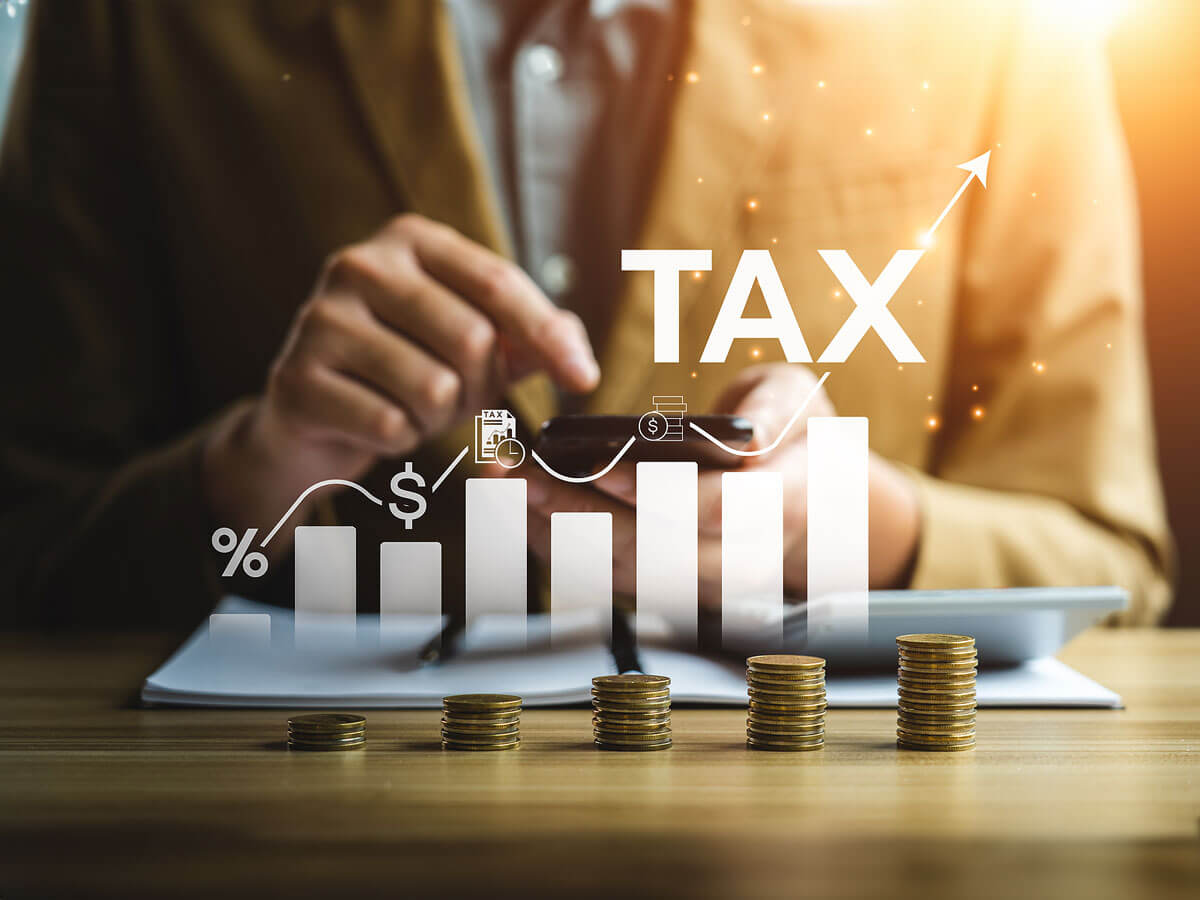 A businessperson uses a smartphone, with digital tax-related icons and a bar graph overlay symbolizing financial growth.