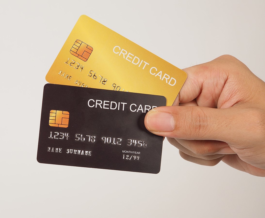 Hand is hold black and gold credit card on white background. Two credit cards.